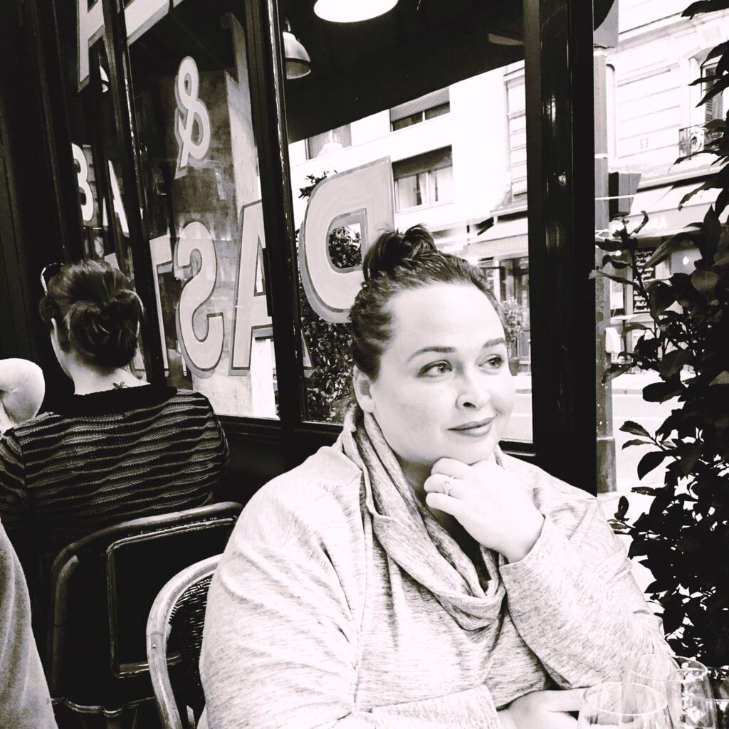 Black and white photo of a woman at a Parisian Cafe looking into the distance