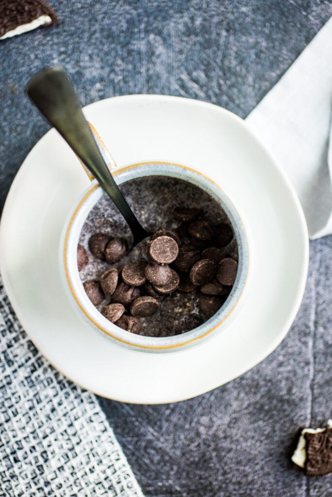 Dark Chocolate Chips on top of Oreo Mug Cake batter in a coffee mug