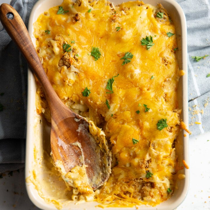 Baked Macaroni and Cheese in a teal baking dish with a wooden spoon resting in the dish